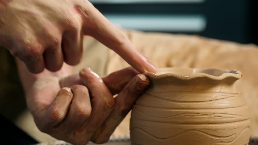 Close up hand man finger craftsman master shaping modeling clay potter pottery wheel craft create decoration details wavy pattern pot workshop hobby professional male making ceramic vase jug forming