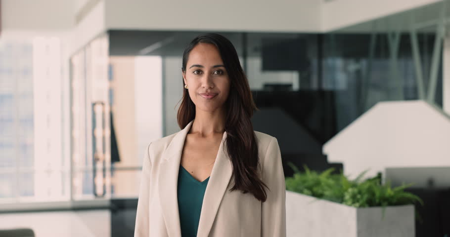 Confident beautiful young New Zealander business leader woman posing for professional headshot in office workspace, crossing arms, looking at camera, getting happy, smiling for portrait, laughing