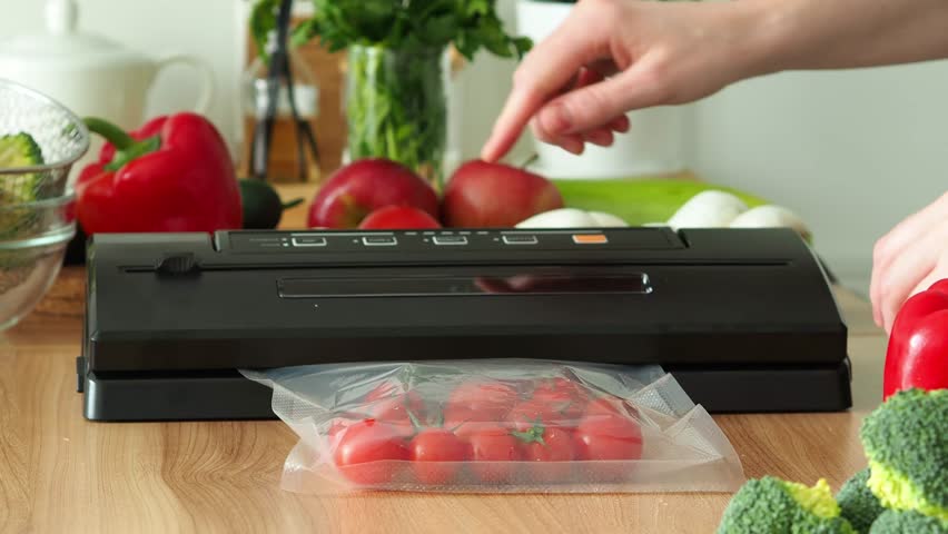 A faceless woman uses a vacuum packaging machine for long-term storage of products. Vacuuming tomatoes for long-term storage. Storage of products. Optimization of space