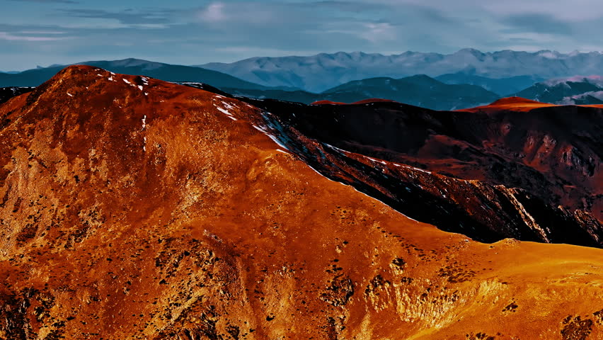 Vibrant colors highlight the rugged terrain of the Pyrenees mountains in Spain. Captured from a drone, the landscape showcases dramatic peaks and valleys.