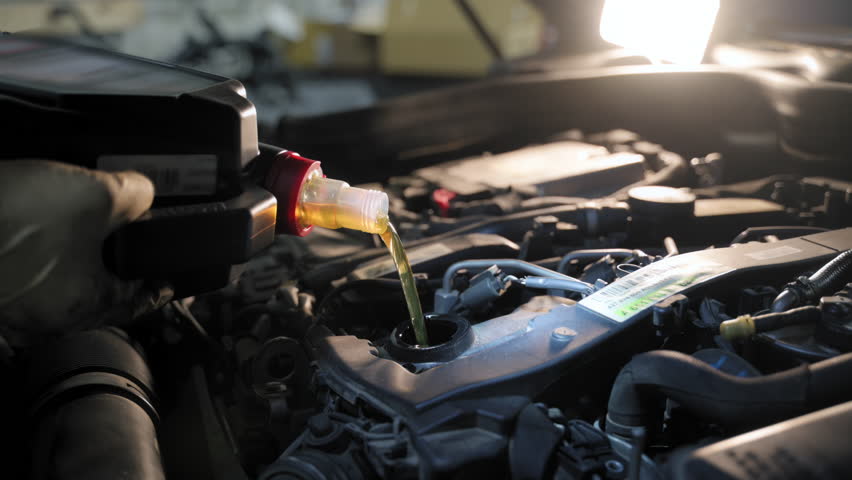 The close-up view of a mechanic changing the car motor oil in a repair shop. During the car inspection or maintenance work