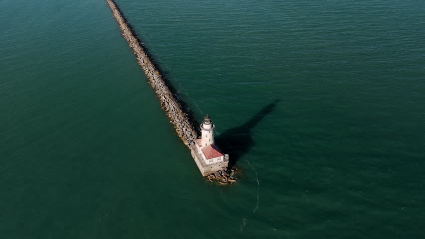 The aerial around view of the sunlit Chicago Harbor Lighthouse . Beautiful sunny day