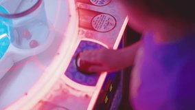 A point-of-view shot of a child playing an arcade game, captured from a slightly elevated angle. The glowing red and blue neon lights illuminate the game console as the child presses the button. - Powered by Shutterstock - Get 15% off with code: PIKWIZARD15