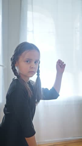 An Expressive Young Girl in a Stunning Black Dress with Beautiful Braids Posing Gracefully. slow motion