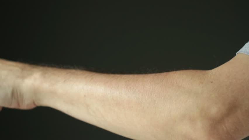 Person scratching at itchy skin on their arms. Profile shot, recorded with