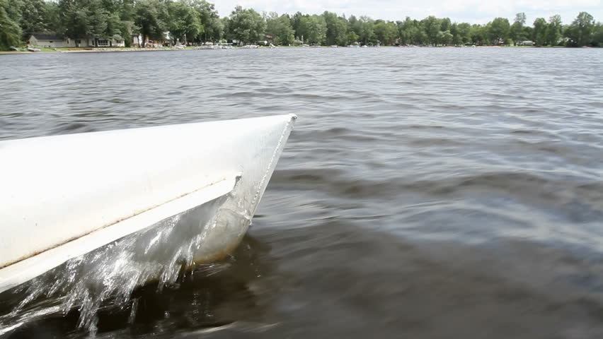 View of a lake looking across the hull of a boat as it moves.