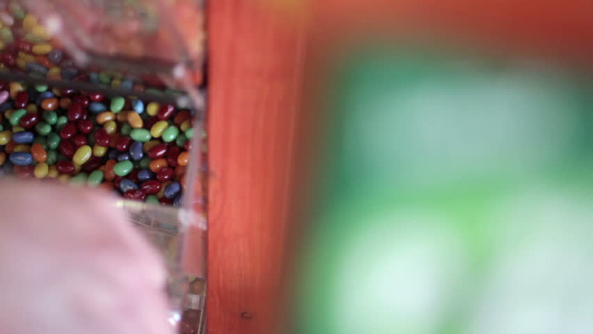 Detail of jelly beans being scooped from a selection in a candy store and into a