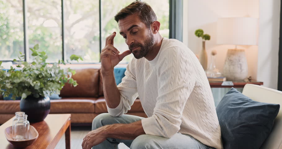 Stress, thinking and man with doubt in home for depression, reflection and worry for financial crisis. Anxiety, sad and person in living room with concern for fail, mistake or mental health challenge