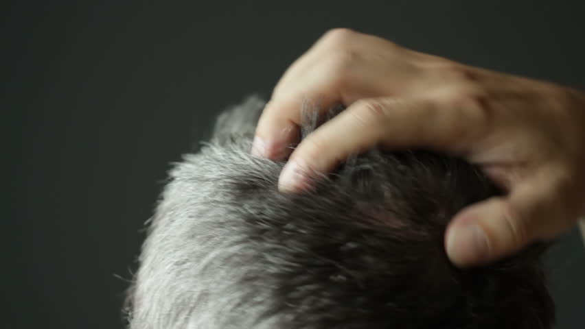Man with grey hair scratching his head. Detail recorded with shallow depth of