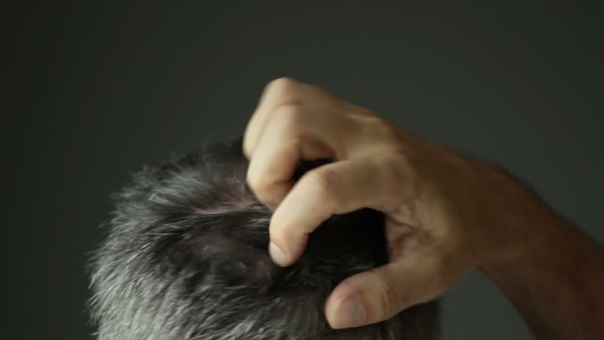 Man with grey hair scratching his head. Recorded with shallow depth of field,