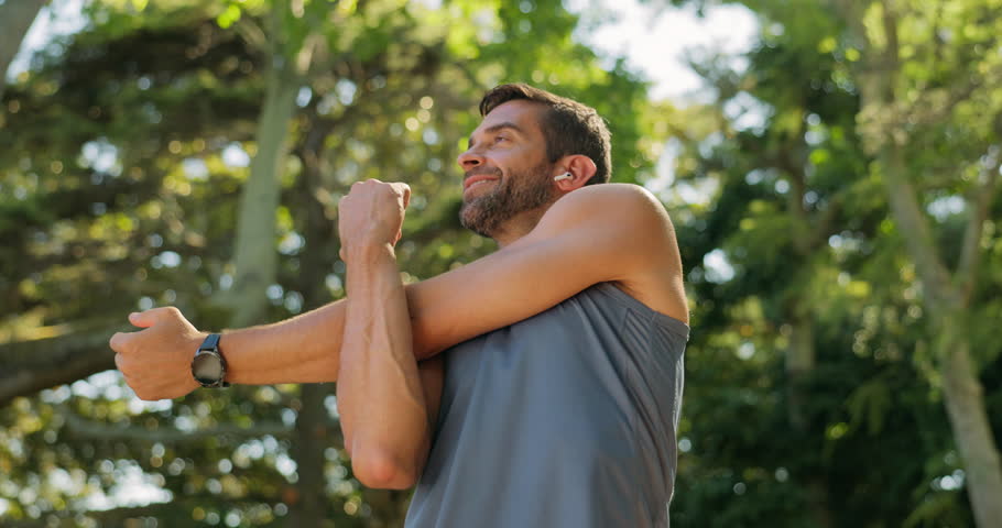 Training, outdoor and man with earphones, stretching or listening to music for fitness or low angle. Routine, athlete and warm up for person in nature, performance or workout with playlist in morning