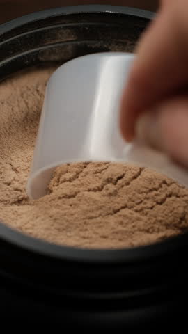 Taking with spoon chocolate protein powder from jar for making protein cocktail