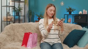 Caucasian shopaholic woman girl at home sofa making online shopping purchase using smartphone and gold credit card. Joyful smiling consumer making digital transaction successful payment, happy feeling - Powered by Shutterstock - Get 15% off with code: PIKWIZARD15