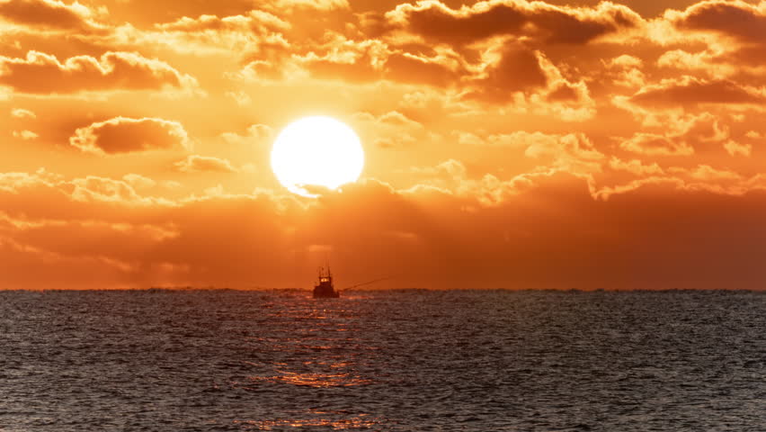 Sunrise Rising over the Horizon with Fishing Boats Moving about on the Sea  (Timelapse)