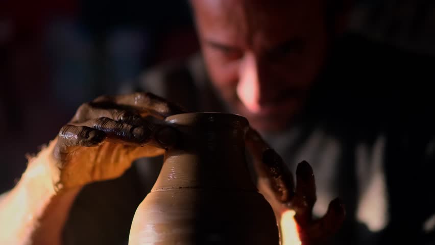 With expert hands,a seasoned artisan molds the clay in close-up detail, creating a beautiful pottery piece.The soft,warm lighting emphasizes the intricate skill of handmade ceramics.