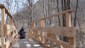 A man in black hooded monk's robes walks on a wooden bridge amidst a forest of bare trees.  - Powered by Shutterstock - Get 15% off with code: PIKWIZARD15