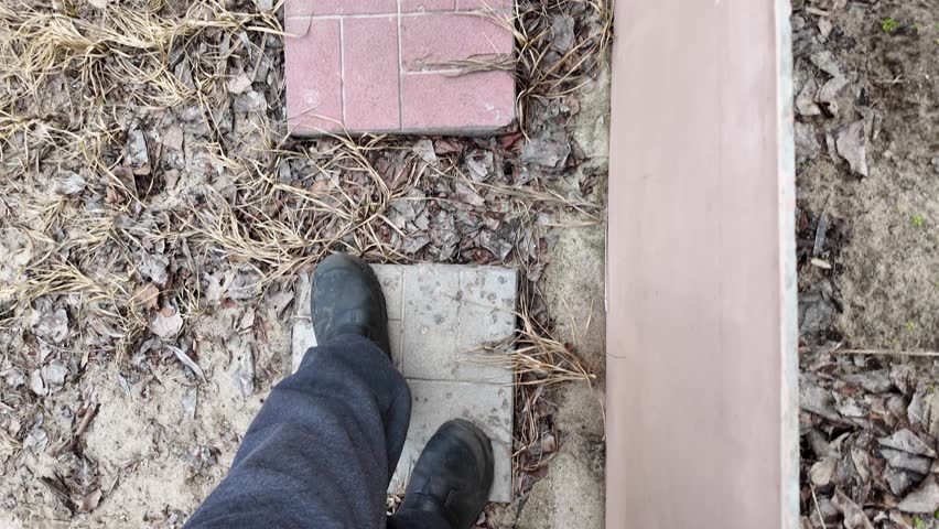 Point of view of a man's feet stepping down a natural wood staircase in a house. First person perspective on home tour concept. old dangerous staircase