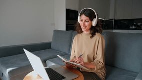 Young smiling woman student working on laptop pc at home remotely. Latin freelance girl entrepreneur in headphones using computer AI app for online remote business studying watching video call webinar - Powered by Shutterstock - Get 15% off with code: PIKWIZARD15
