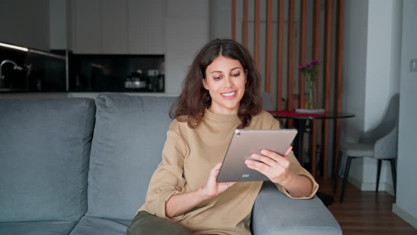 Freelance business woman sitting on sofa using tablet computer application for work remotely. Latin hispanic girl holding tab gadget, working at home, browsing, chatting, shopping online. Copy space - Powered by Shutterstock - Get 15% off with code: PIKWIZARD15