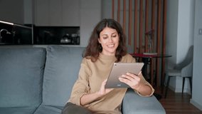 Freelance business woman sitting on sofa using tablet computer application for work remotely. Latin hispanic girl holding tab gadget, working at home, browsing, chatting, shopping online. Copy space - Powered by Shutterstock - Get 15% off with code: PIKWIZARD15
