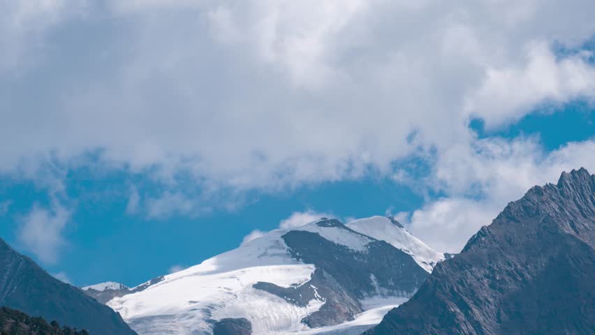 4K Time Lapse shot of dark stormy clouds moving above the Lady Of Keylong mountain peak as seen from Keylong in Lahaul, Himachal Pradesh, India. Mountain peak covered with glacier. Nature landscape.