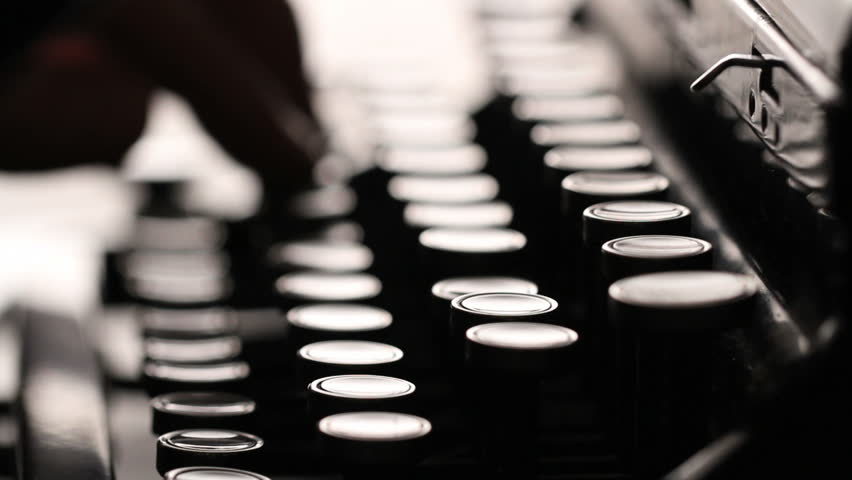 Macro view of a person typing on a manual typewriter. Strong backlighting.