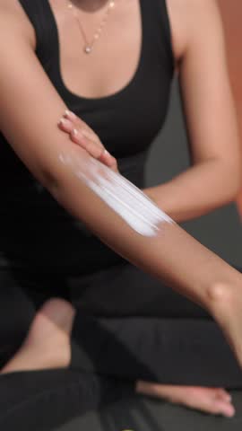 Young Asian woman applying moisturizing sunscreen lotion on face and body before exercising outdoor.