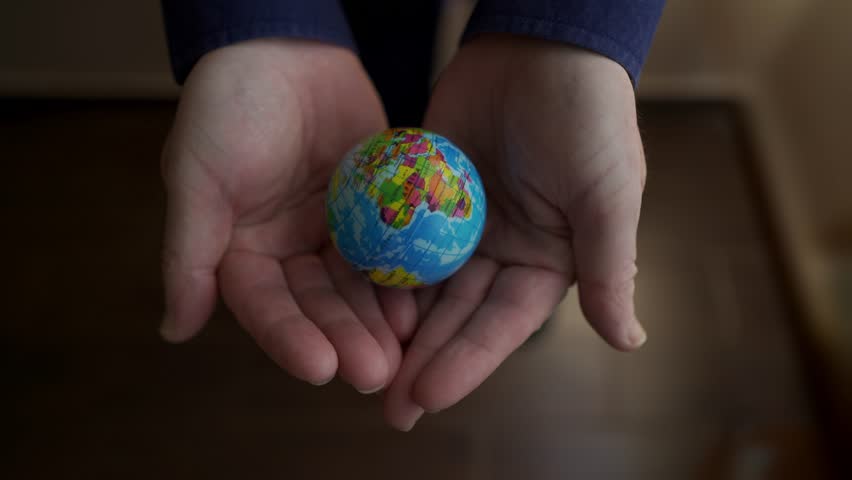 Businessman holding small earth globe in open palms