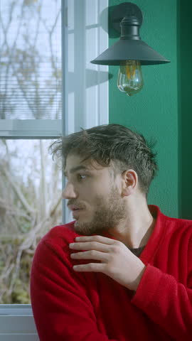 Young man in a red sweater having a sudden lightbulb moment as an idea strikes him, with a symbolic glowing bulb turning on above his head, representing inspiration and creativity in a cozy indoor set