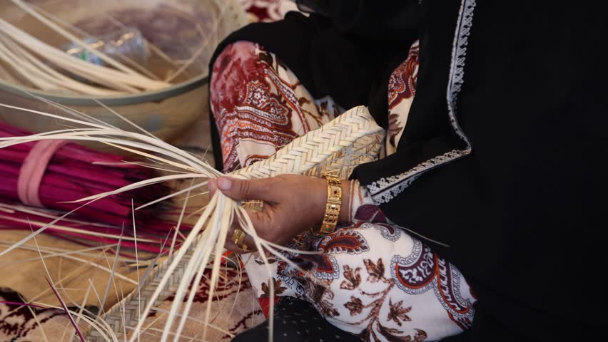 Emirati woman weaving traditional basket from palm leaves, hands in frame. High quality 4k footage.