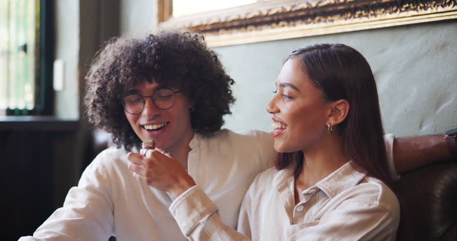 Smile, love and feeding couple chocolate in cafe for romance, dessert and laugh together. Man, woman and eating sweets on date in restaurant for valentines day celebration, talk or happy with treats
