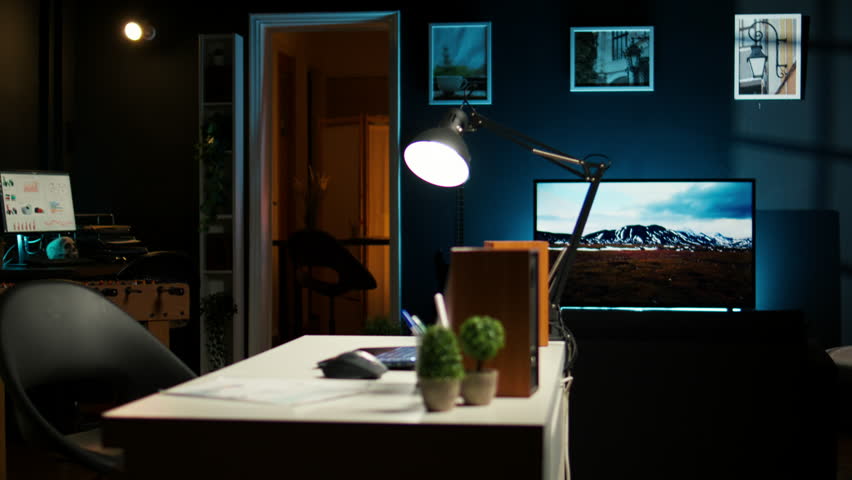 Empty yet inviting home office in a contemporary illuminated apartment. Wooden floors, modern furniture and decorative plants creating a cozy workspace for studying or working indoors.