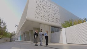 Three diverse business professionals walking and discuss ideas outside a contemporary building, promoting teamwork and innovation on a sunny day - Powered by Shutterstock - Get 15% off with code: PIKWIZARD15