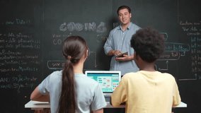 Professional teacher holding tablet while explain about programming system at blackboard while teenager with mixed raced working on laptop by coding program in back view at STEM class. Edification - Powered by Shutterstock - Get 15% off with code: PIKWIZARD15