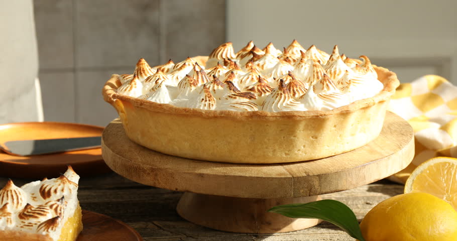 Woman cutting and serving lemon meringue pie at wooden table, closeup