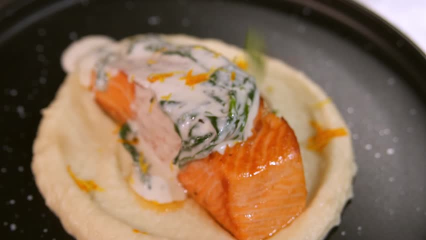 Chef spreads sauce on salmon. Slow motion.