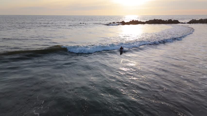Surfer Riding a Wave at Sunset in Venice Beach, Los Angeles