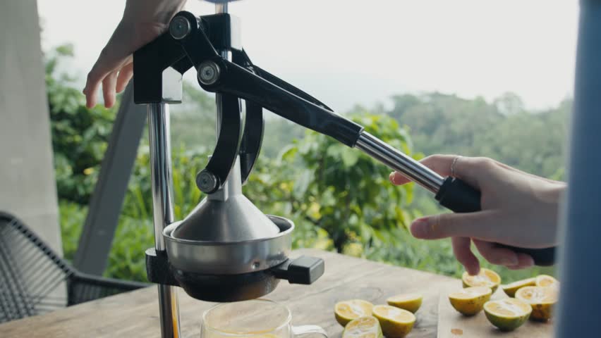 Chef squeezing fresh orange juice with manual citrus press