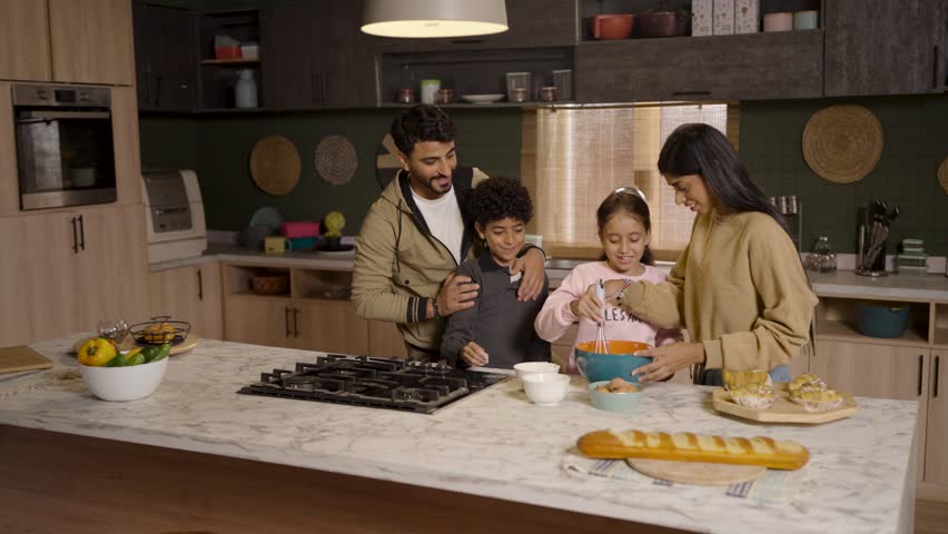 A joyful family—father, mother, son, and daughter—gather in the kitchen, happily baking together and creating cherished memories.