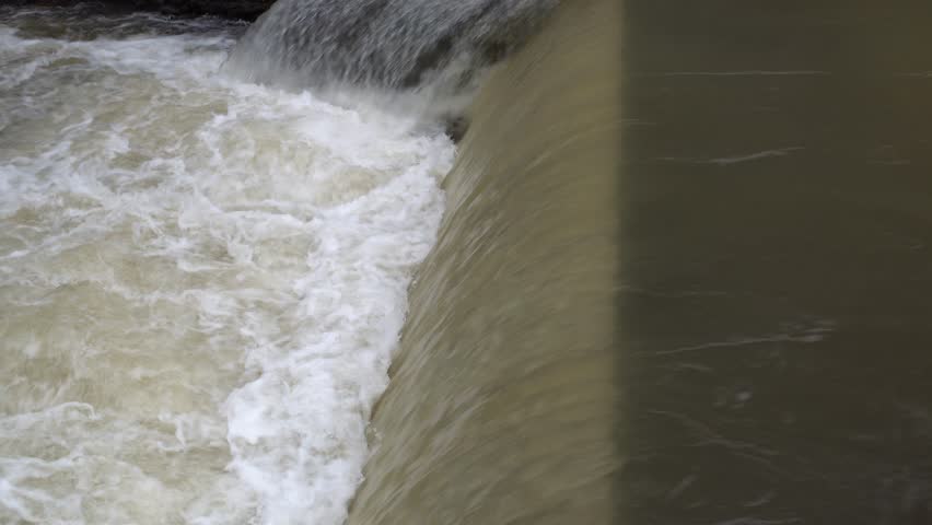 Industrial waterfall line Dam with foamy water flow closeup front side view, water flow from right to left.