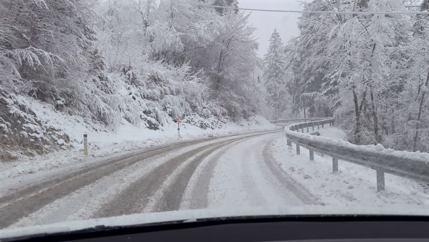 POV footage from inside a vehicle approaching a sharp curve on a snow-covered forest road.