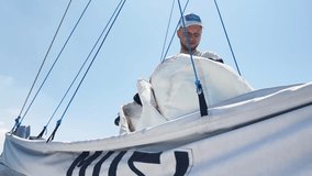 Male captain on deck of sailboat opening sails pulling the rope - Powered by Shutterstock - Get 15% off with code: PIKWIZARD15