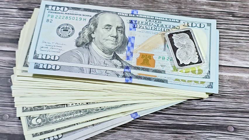 USD American dollars cash money and silver precious metal ounce bar of pure silver, The price of silver is driven by speculation, supply and demand and it