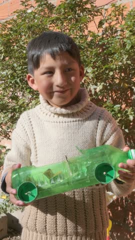 vertical latin boy holding a car made of recycled plastic bottle in la paz -bolivia latin america - recycling concept