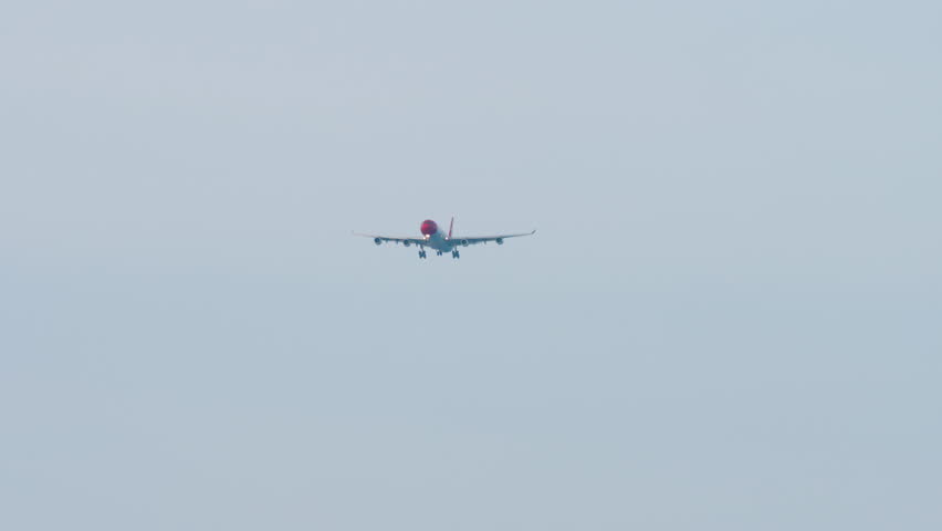 Jet passenger plane with an unidentified livery descending for landing against the blue sky