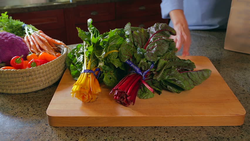 Woman unpacking chard and kale in kitchen