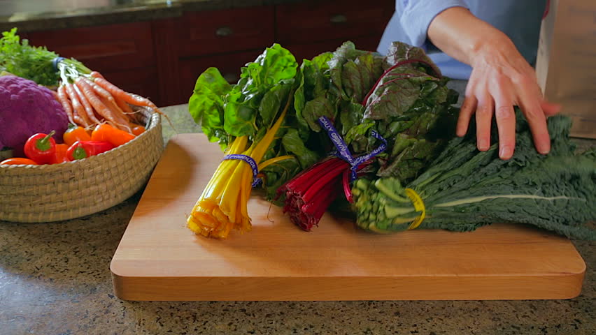 Woman unpacking chard and kale in kitchen