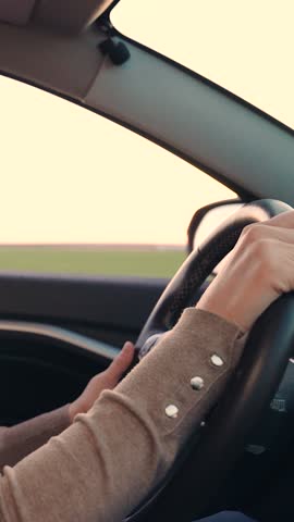 Female hands control steering wheel of car closeup. People driving their car. Human goes to work by car. Woman travels by car outside city, drives auto. Luxury vehicle rental insurance. Nice way home