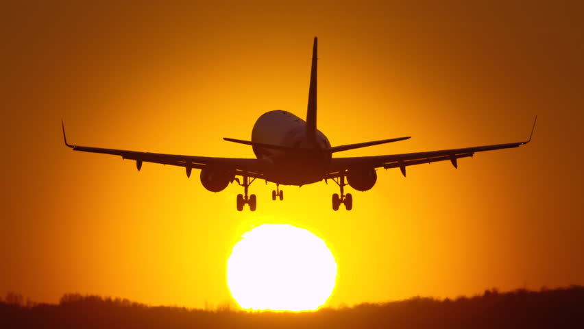 Passenger plane landing during sunset at a busy airport, showcasing travel and tourism