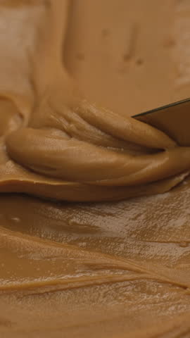 Peanut butter scooping with a golden knife. Perfect breakfast with peanut butter